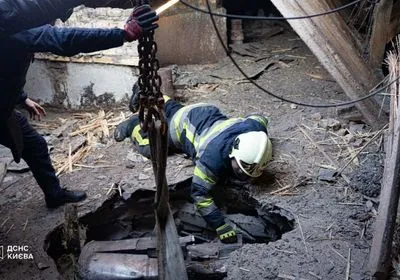 Rescuers remove a part of a Russian missile from a residential building in Kyiv's Pechersk district